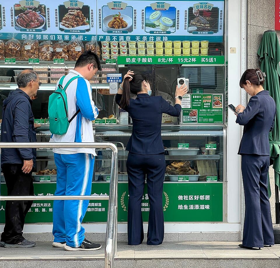 A woman at Beijing's Ziguangyuan restaurant holding a payment QR code toward a countertop scanner