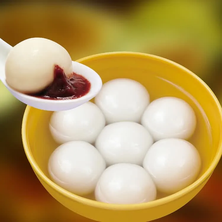 White glutinous-rice balls in a yellow bowl, with one on a spoon beside a dark red accompaniment.