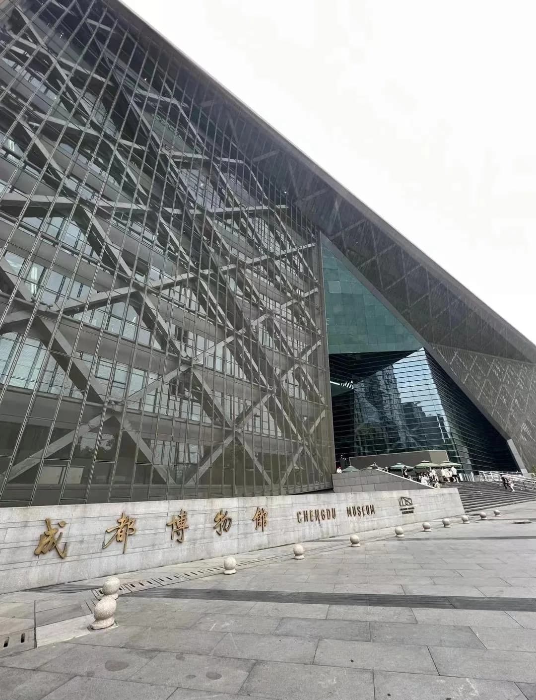 The angular glass facade and entrance steps of Chengdu Museum, with the museum name on a stone wall.