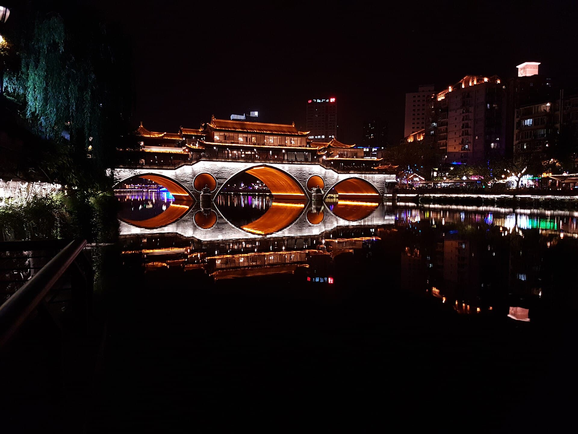 Anshun Bridge lit up at night, reflected in the river in Chengdu