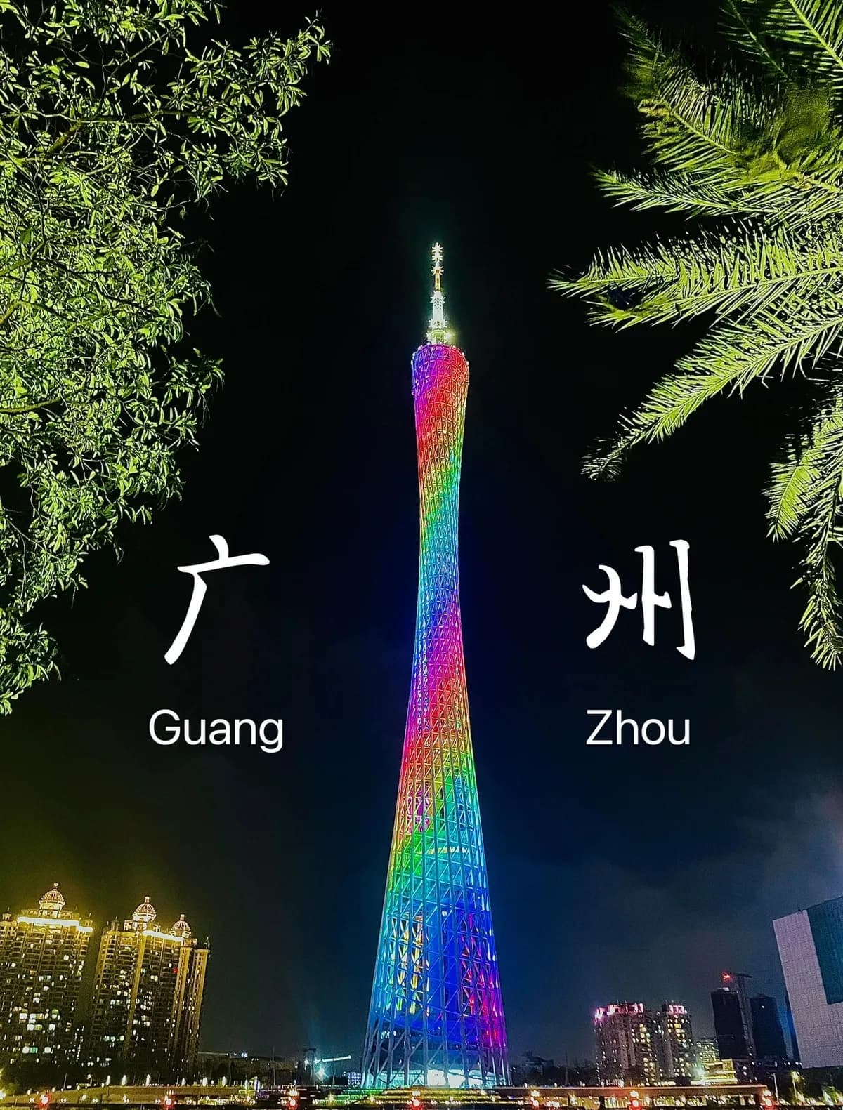 Canton Tower illuminated in rainbow colors at night, framed by trees, with decorative Guangzhou lettering.
