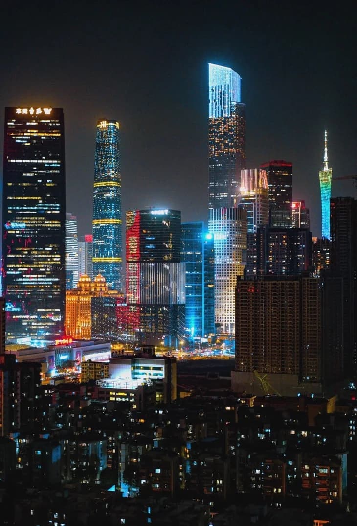Illuminated towers in Zhujiang New Town at night, with Canton Tower visible in the distance.