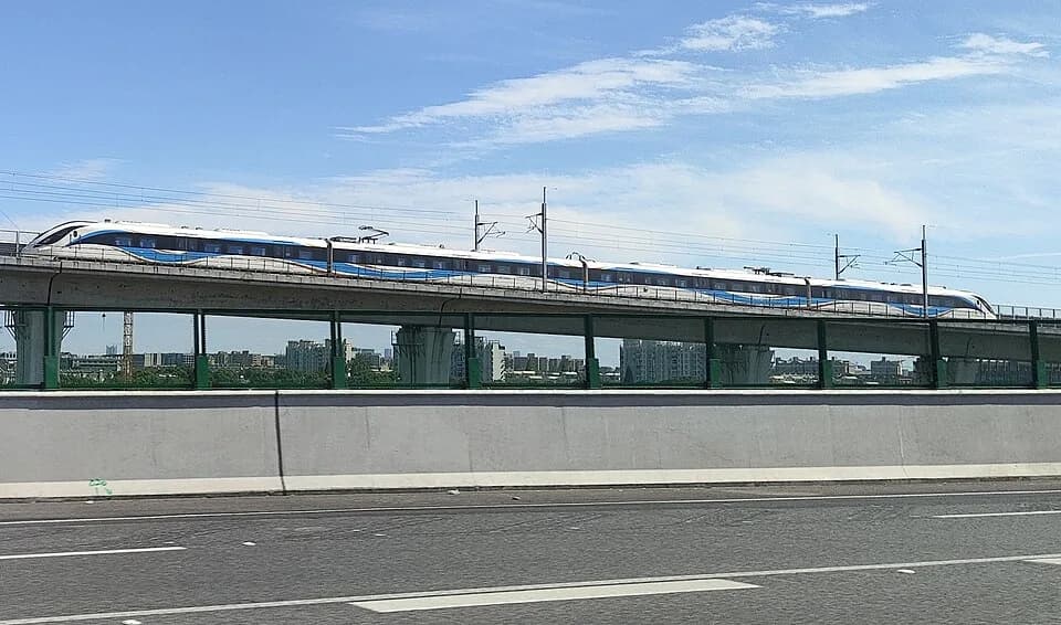 A blue and white Airport Link Line train on an elevated railway.