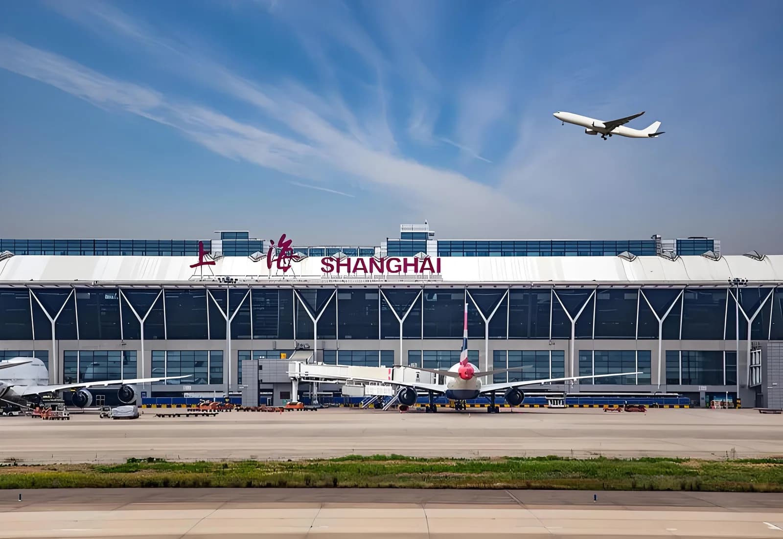 Aircraft beside an airport terminal bearing red Shanghai lettering.