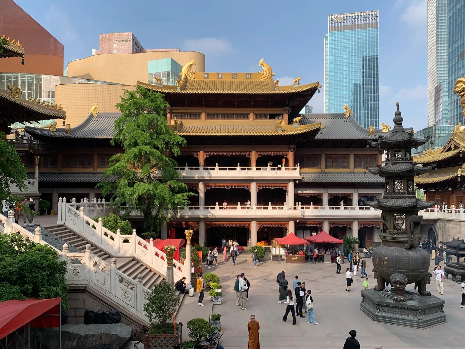 Golden-roofed hall and courtyard at Jing’an Temple, with city towers behind it.