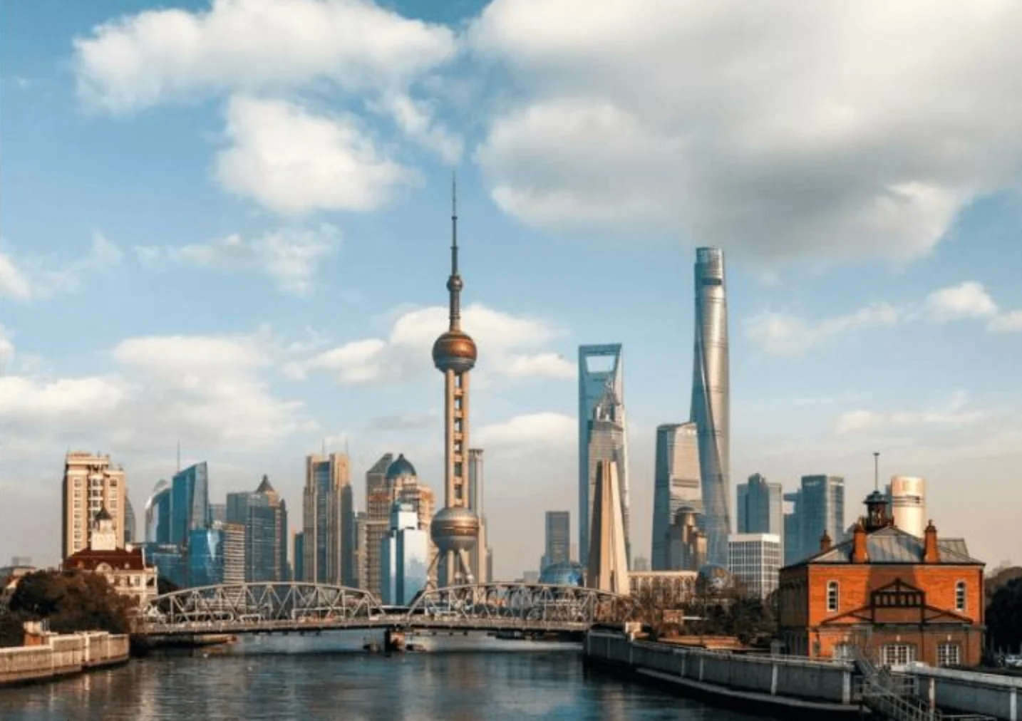 Lujiazui towers behind a steel bridge and river, including the Oriental Pearl Tower and Shanghai Tower.