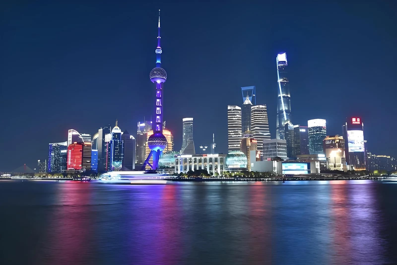 The illuminated Oriental Pearl Tower and Lujiazui skyscrapers across the Huangpu River at night.