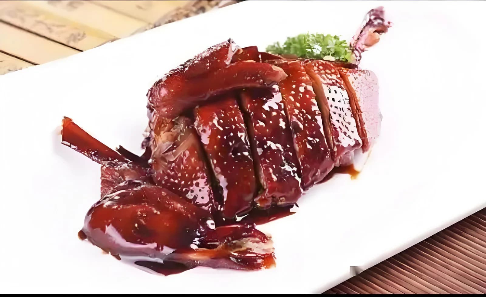 Sliced duck with a dark glaze on a white rectangular plate.