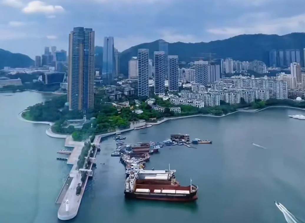 Boats, piers and waterfront buildings at Taizi Bay in Shekou, Shenzhen, with hills behind them.