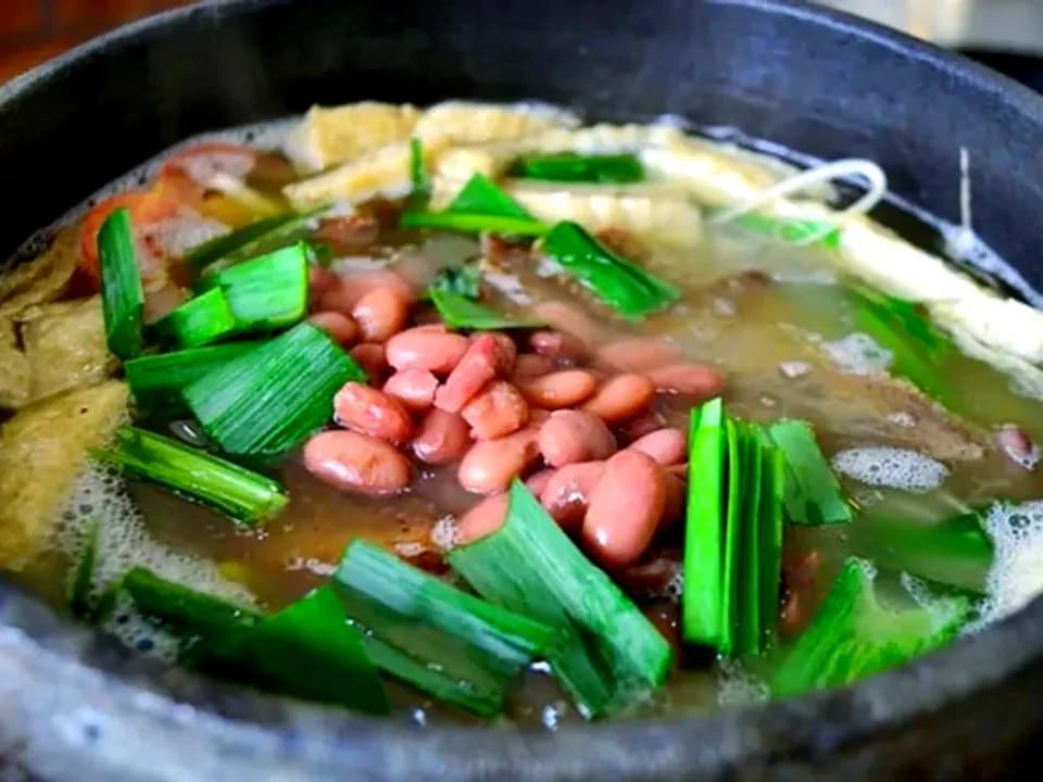 Guizhou bean hotpot with red kidney beans, tofu and fresh chives in a black stone pot