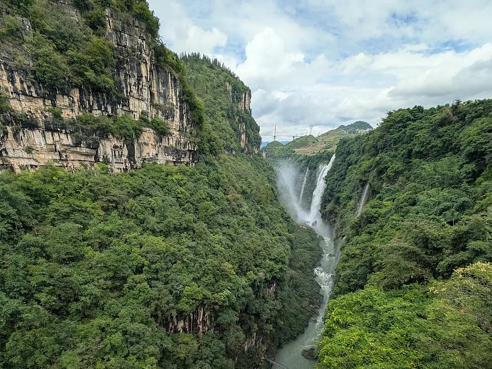 Steep green walls, a narrow river and several waterfalls inside Malinghe River Canyon near Xingyi