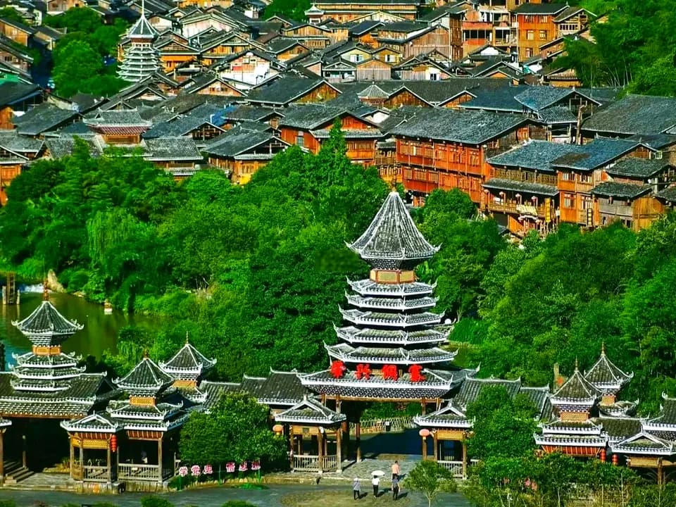 Wooden houses and several tiered drum towers filling the green valley at Zhaoxing Dong Village in Guizhou